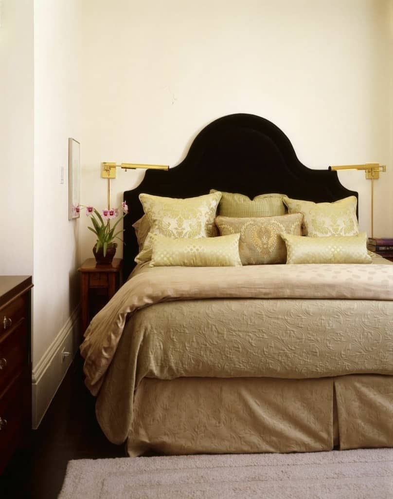 A small grand bedroom making the use of golden bedroom and bed sheets creates richness. The beautiful black headboard and deep colored floor create great contrast to the white walls and golden bed sheet.