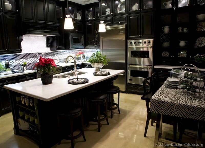 Black upper and lower cabinets create a bar-like atmosphere in this modern kitchen. The white marble island countertop and the ornate cabinet tops stand out from the dark. The shiny marble floor complements the white island top.