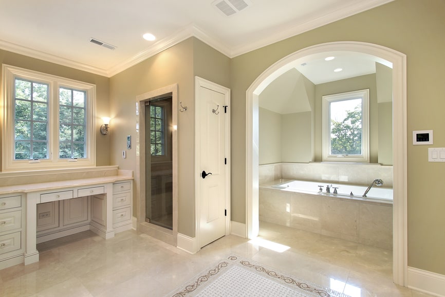 A bathroom that uses light textured floor tiles and Sandal colored wall. There is arched doorway to enter the main shower area that hosts a bathtub .