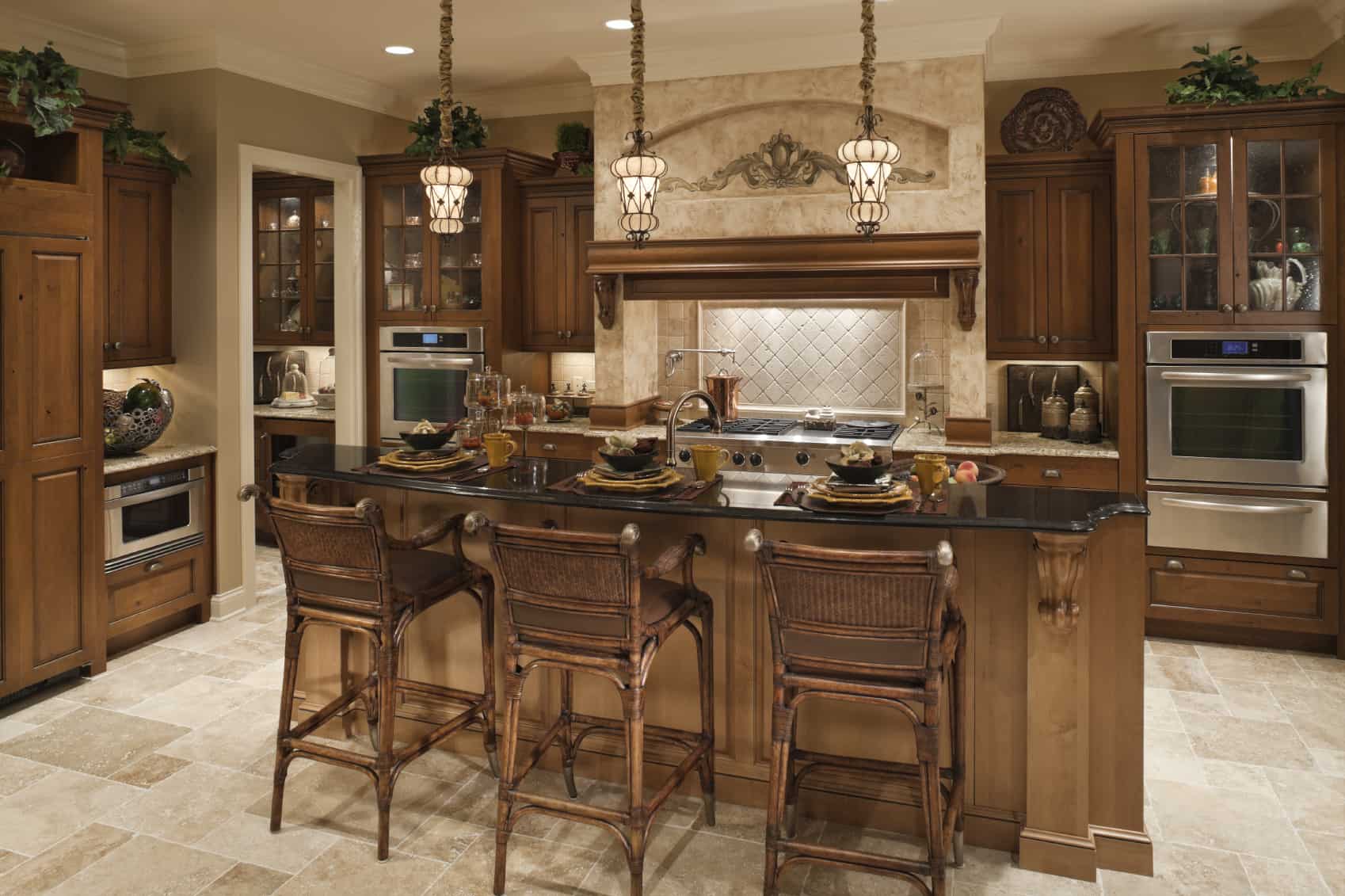 The large wooden island is the center of this kitchen. The thin layer of black marble countertop creates a contrast from the tiles floor of beige color.