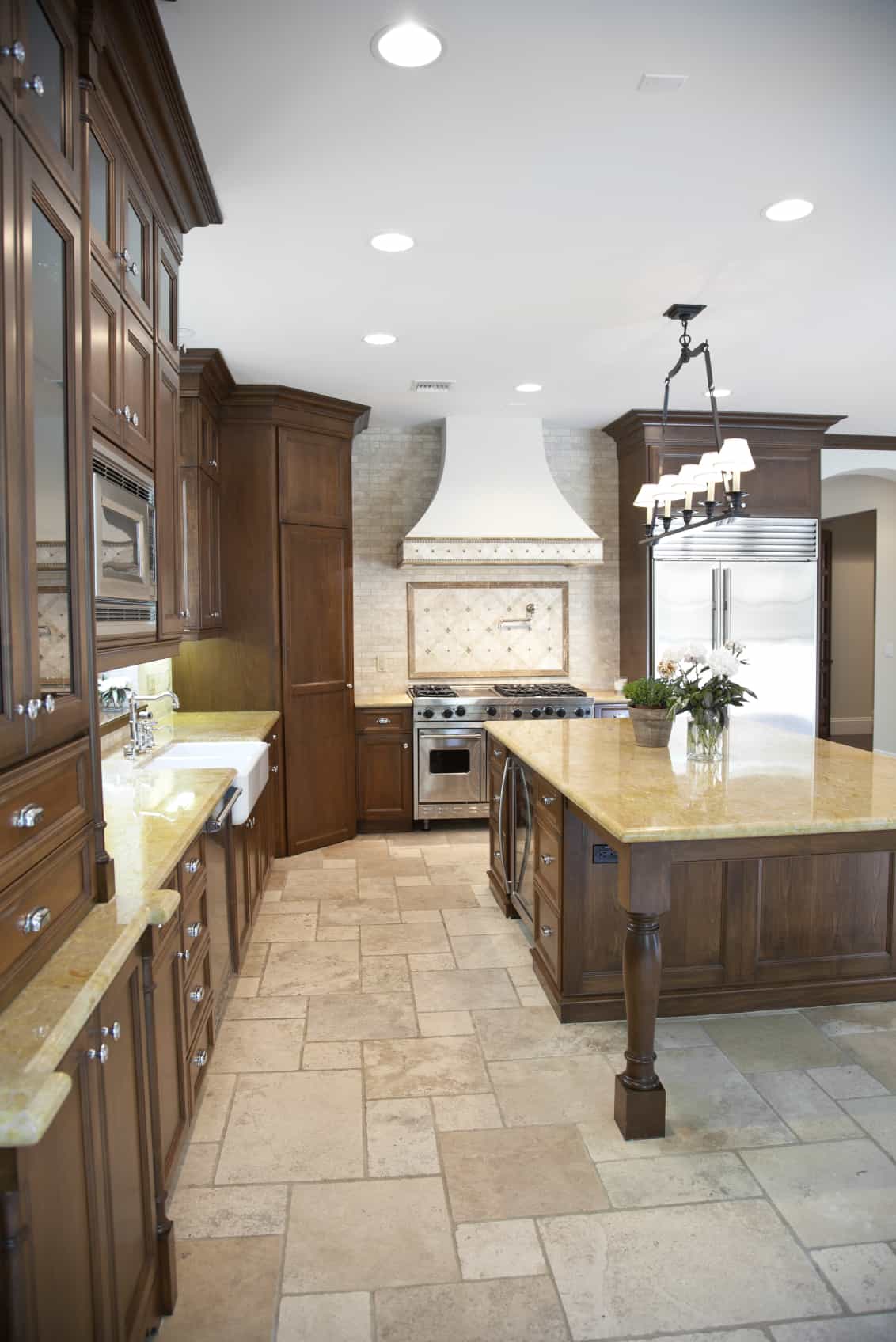 Light stone flooring makes the natural wooden cabinets and island pop even more.