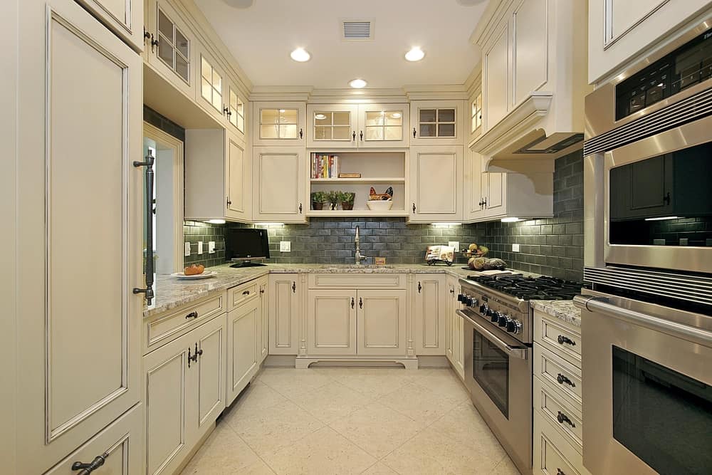 This is another kitchen with white cabinetry and aluminum appliances that feature upper cabinet cupboards.