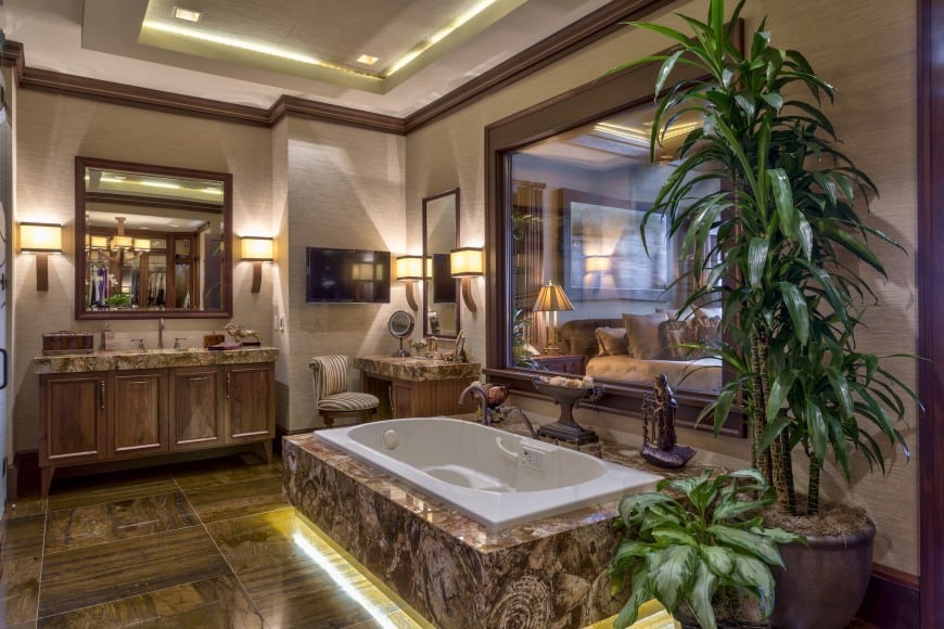 An ultra-modern master bathroom centered around a cozy Jacuzzi. The accent of the large marble tiles is quite unique . The marble topped vanity uses dark wood . The artistically placed antiques and large potted plants add to the upscale style of this master bath.