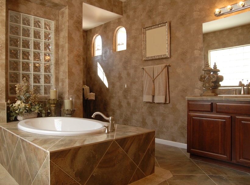 A masculine bathroom with a central bathtub with an ornate glass shelf closeby. The copper color is featured in this bathroom.