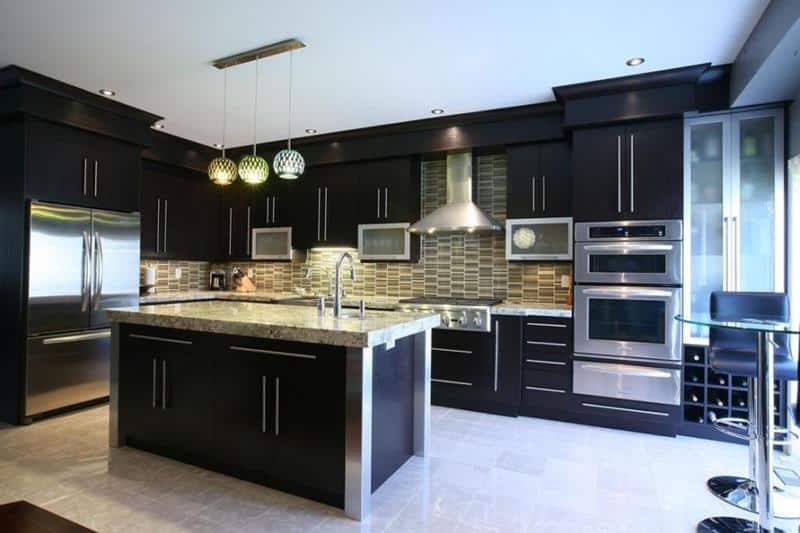 A stylish modern kitchen with deep blue cabinets and island contrasting the granite countertop .