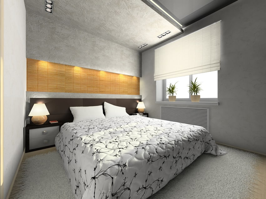 A small bedroom centered around the simple bed . The wall behind the bed is finished with a metallic grey wall paper up to the ceiling with a rectangular artistic portion with a golden glow.