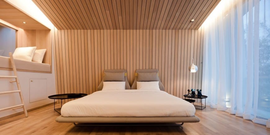 The wooden wall with vertical lines make the room look taller than it actually is and enhances the style of the bedroom even more.