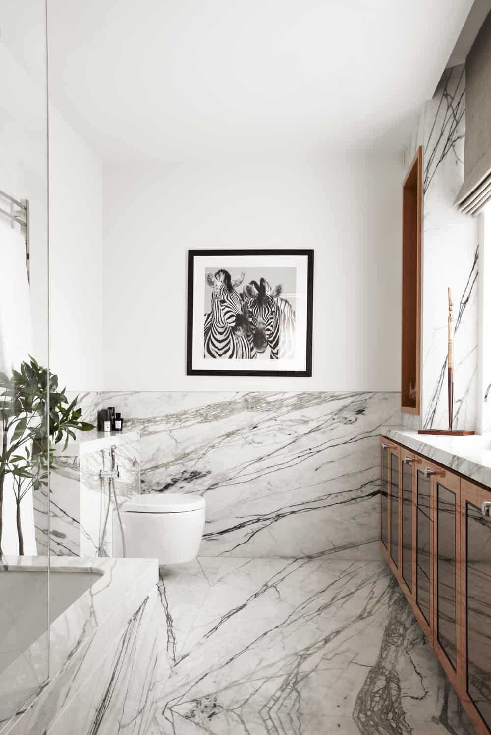 Have a look at this wonderful bathroom ! It makes a bold artistic statement with rich-veined marble all around. This together with the wooden cabinet creates a warm feeling of belongingness. The zebra art and the overall feel is mesmerizing in natural light.