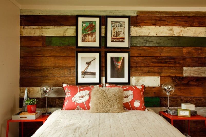 A country bedroom design with rustic wall hosting many colors. The bed too has some fun-colored pillows. A custom-made bedroom at its very best.