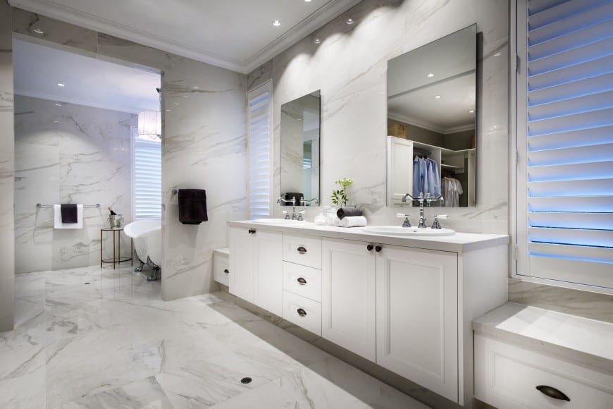A truly upscale large bathroom with rich marble floor and walls. The vanity of made to match . The traditional claw-foot tub is placed in separate room. 