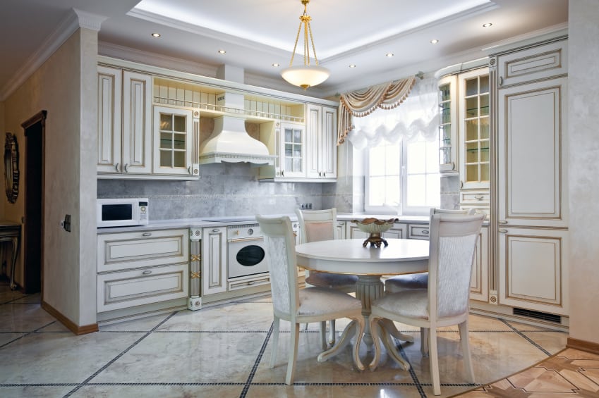 An artistic kitchen with sumptuous gold & white textures and borders throughout. The marble flooring has a diagonal texture .