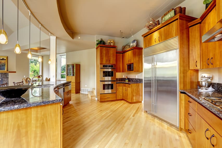 It is the unique layout of the kitchen that makes it look even bigger. The arch shaped island can serve and entertain lots of guest at a time . The cabinet have nice teak wood textures which adjusts rather well with the granite countertops. The beech wooden floors act as a horizontal backsplash for the bold and charismatic colors used .