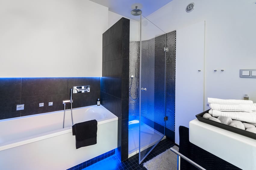 A pretty masculine bathroom that uses modern minimalist styles. The floor uses black mosaic tiles. The walls are white in most part with some patches of dark grey shades. The shower area uses rare stainless steel mosaic tiles.