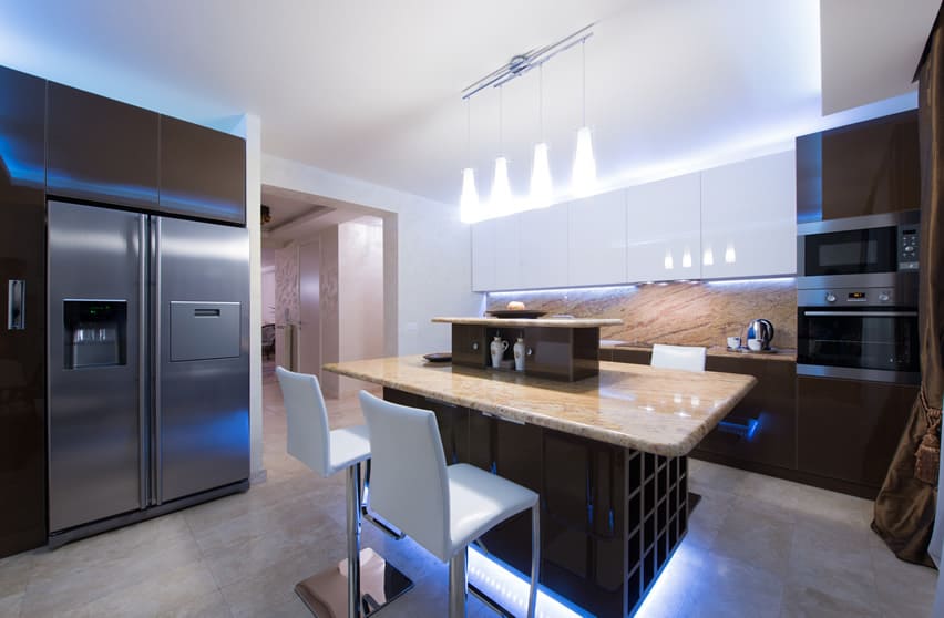 Extremely classy kitchen with spot lights placed in the base of island and on the ceiling that brightens up the atmosphere. The cabinets have glossy solid brown finishing. As usual , the appliances are aluminum finished .