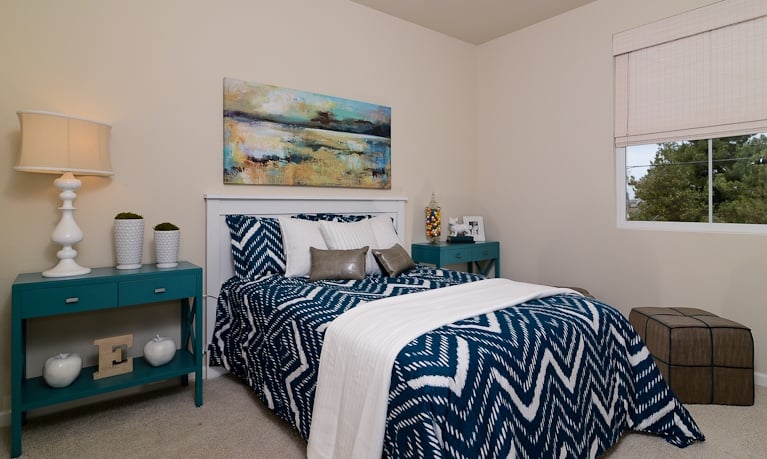 The extensive use of dark and deep colors make this small bedroom pop . The neutral walls make the midnight blue colors pop even better.