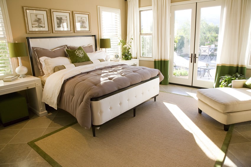 A stylish classy bedroom with green , grey and tan color combines magnificently. There are several big windows and doors around the room . The green accents on almost all the furniture creates a relaxing atmosphere.
